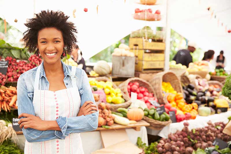 Woman standing next to vegetable stand